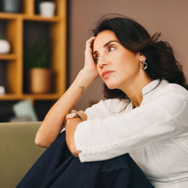 A woman sitting on her couch overthinking representing How to Stop Overthinking and Find Inner Peace
