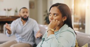 Woman looking frustrated while partner talks during a disagreement – illustrating “I don’t like you but I love you” relationship moments.