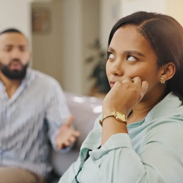 Woman looking frustrated while partner talks during a disagreement – illustrating “I don’t like you but I love you” relationship moments.