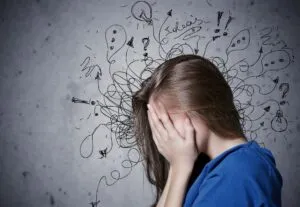 Woman covering her face, surrounded by chaotic scribbles and question marks, symbolizing the overwhelm of undiagnosed ADHD