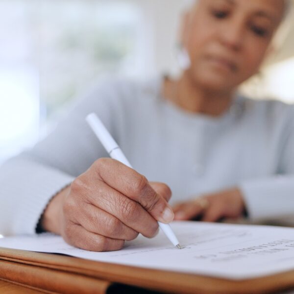 A therapist writing and signing documents, symbolizing the importance of creating a professional will for therapists to ensure ethical continuity of care.