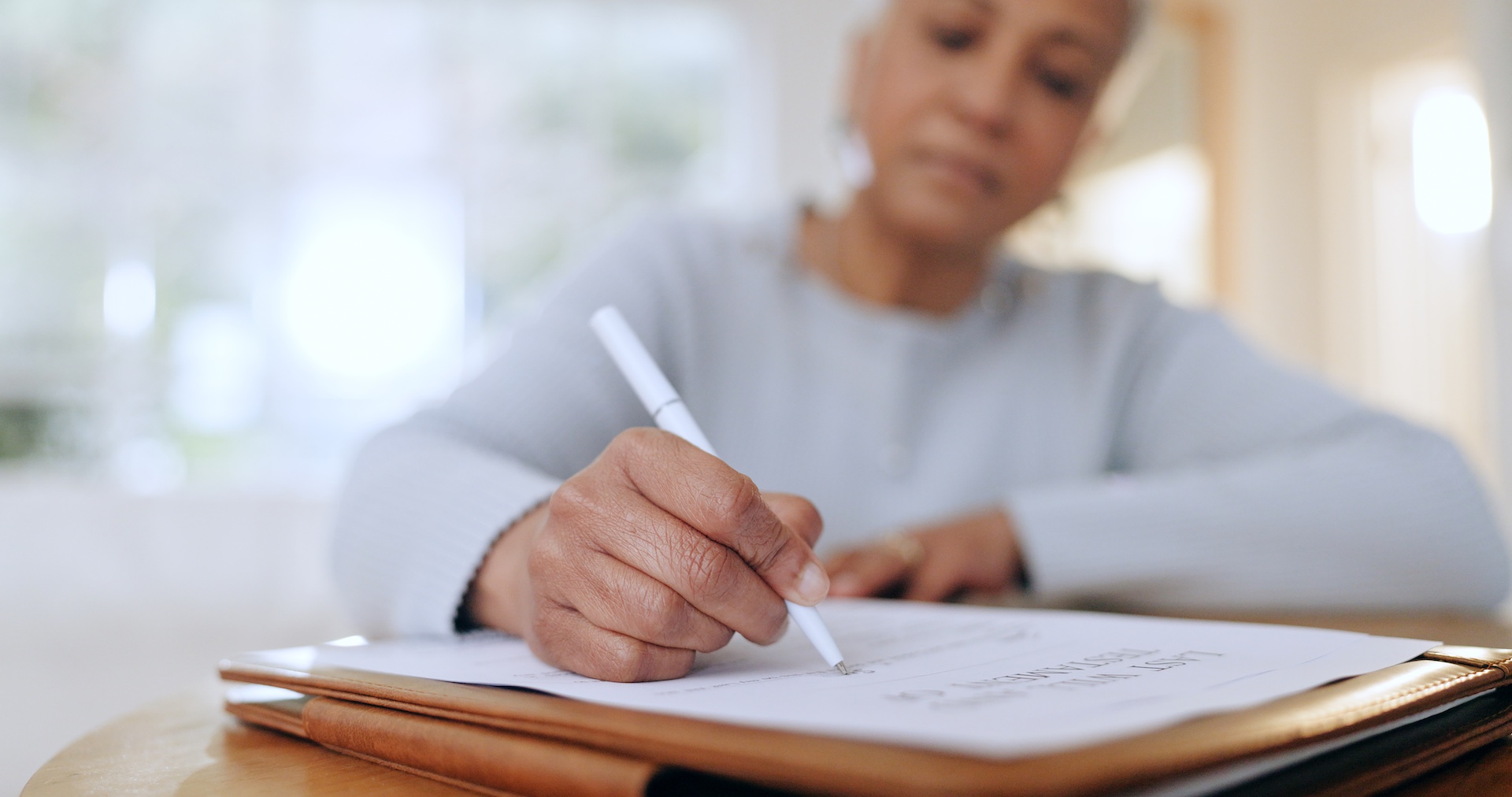 A therapist writing and signing documents, symbolizing the importance of creating a professional will for therapists to ensure ethical continuity of care.