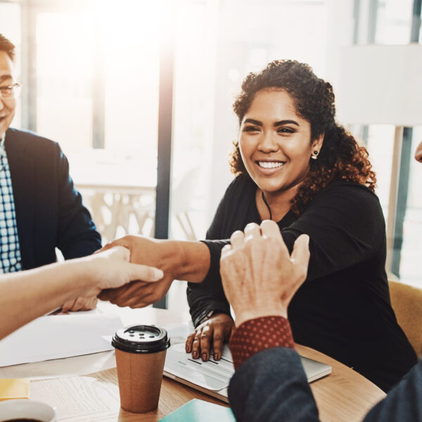 Smiling woman shaking hands in a business meeting, symbolizing trust, connection, and influential leadership.