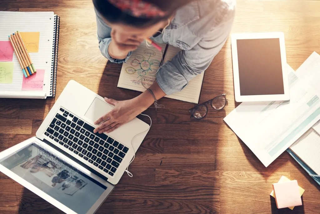 Entrepreneur planning on laptop with notes and sketches, showing what it takes to be an entrepreneur in business.