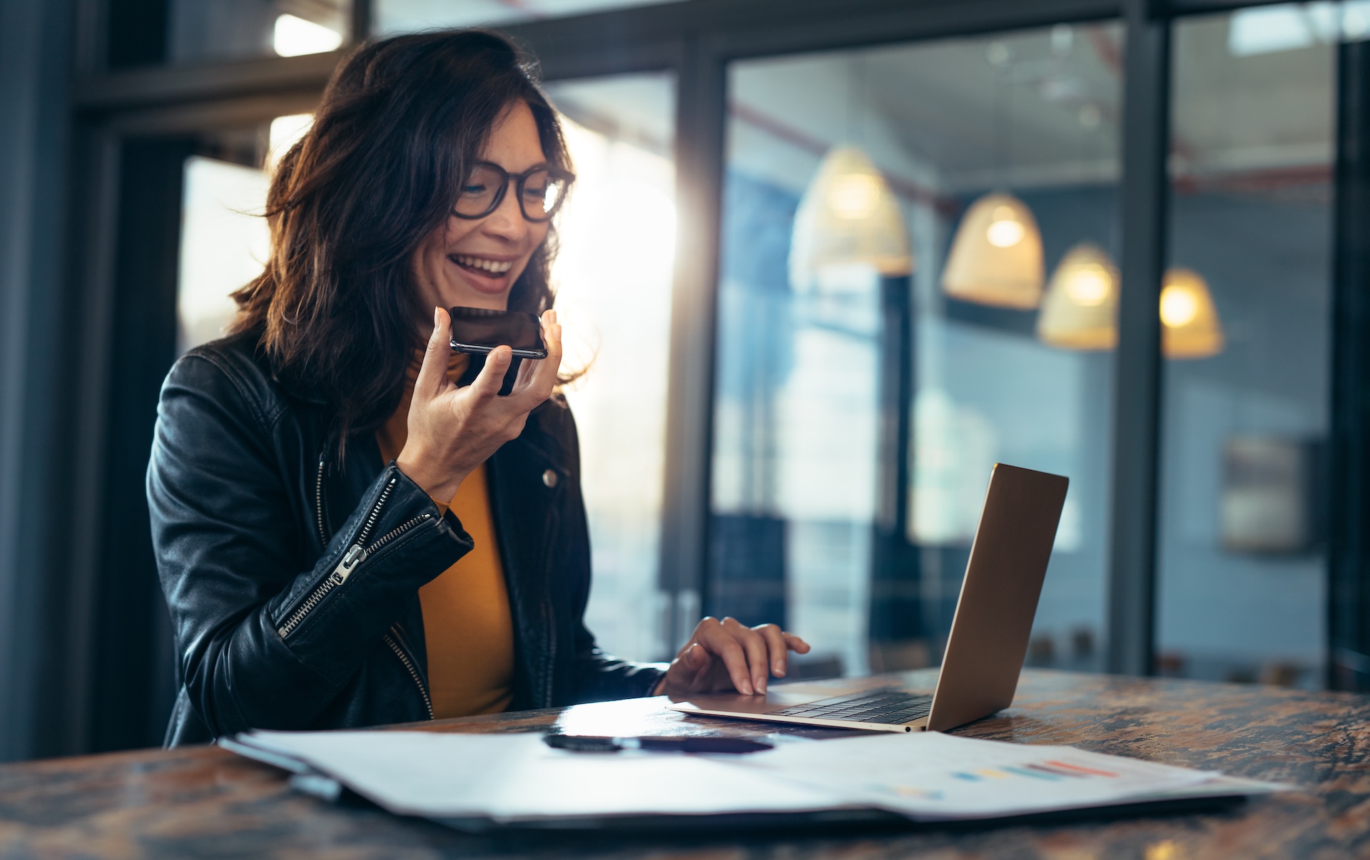Therapist with an entrepreneurial mindset smiling while running her private practice business on a laptop and phone.