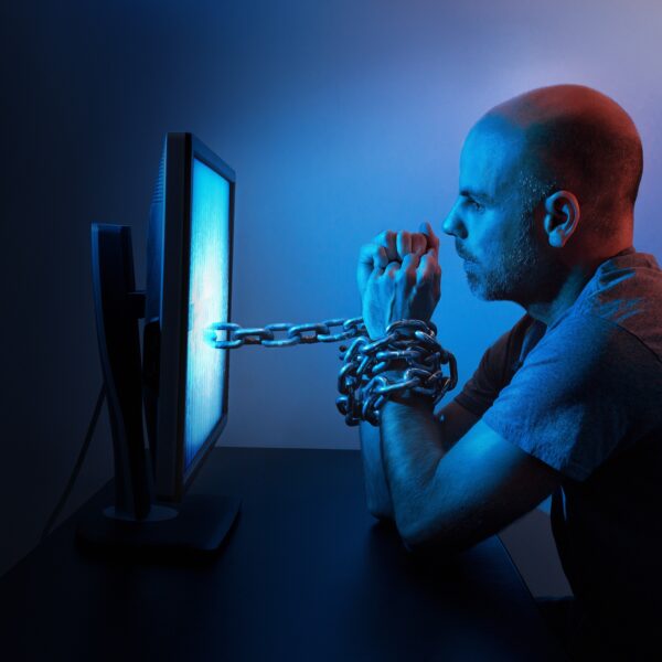 A man chained to a computer screen symbolizing porn addiction and its impact on relationships.