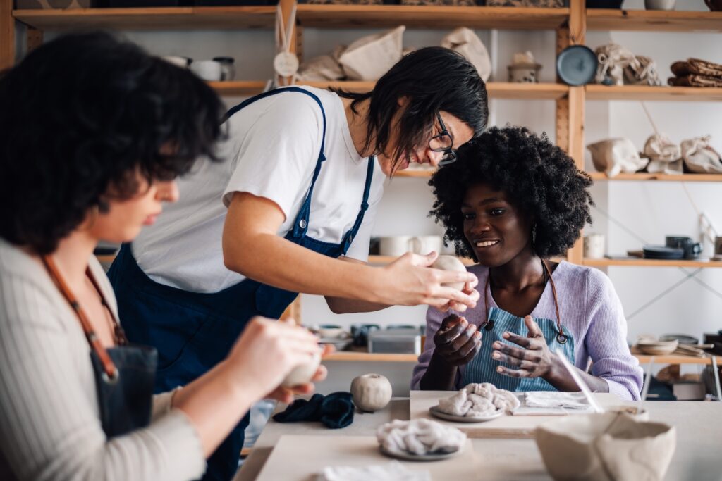 People forming human connection in a pottery workshop, working together and improving their social wellness while overcoming loneliness.