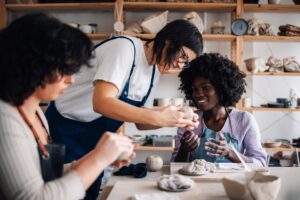 People forming human connection in a pottery workshop, working together and improving their social wellness while overcoming loneliness.