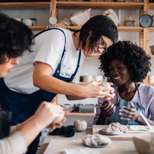 People forming human connection in a pottery workshop, working together and improving their social wellness while overcoming loneliness.