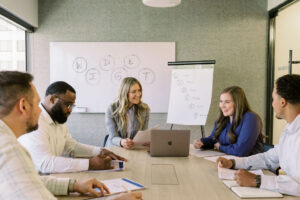 Team discussion around a table reviewing the six types of working genius framework during a collaborative work meeting.