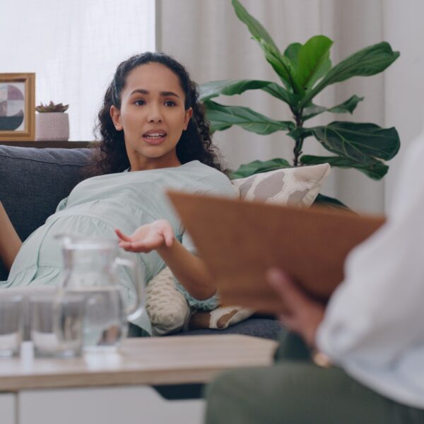 Pregnant woman speaking with a therapist during a counseling session, illustrating perinatal mental health support in therapy.