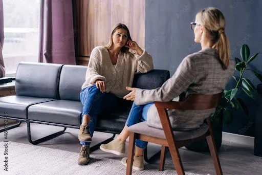 Therapist and client sitting in a counseling office, engaged in a focused conversation during a therapy session.