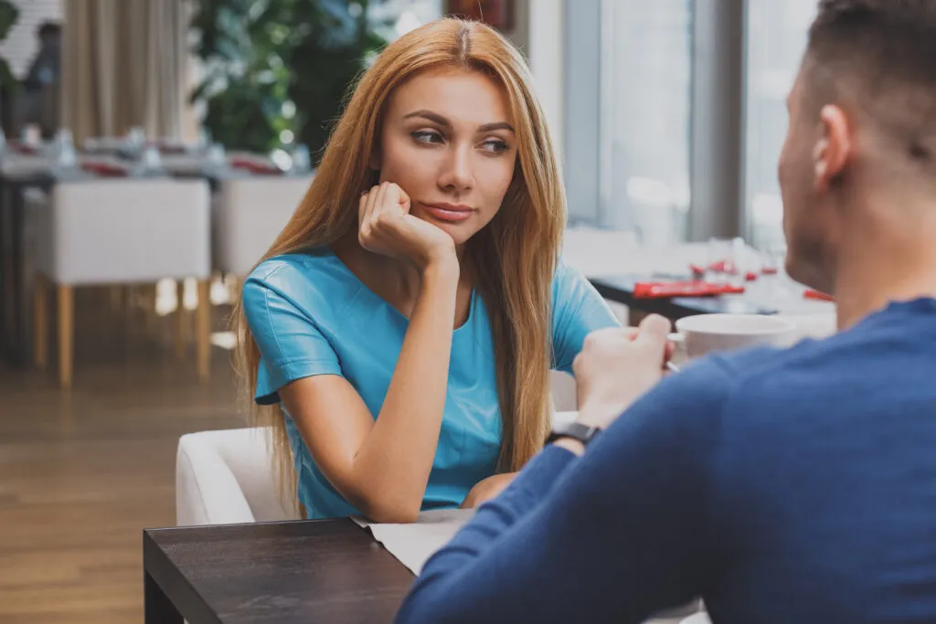 Woman and man talking across a table at a café during a first date, illustrating modern dating and in-person connection.
