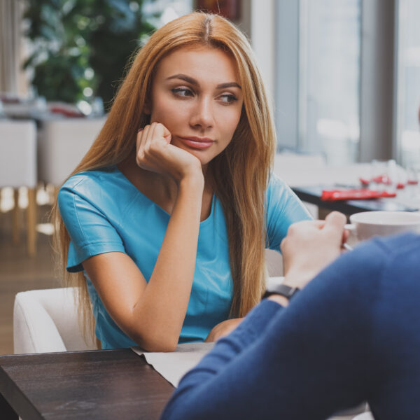 Woman and man talking across a table at a café during a first date, illustrating modern dating and in-person connection.