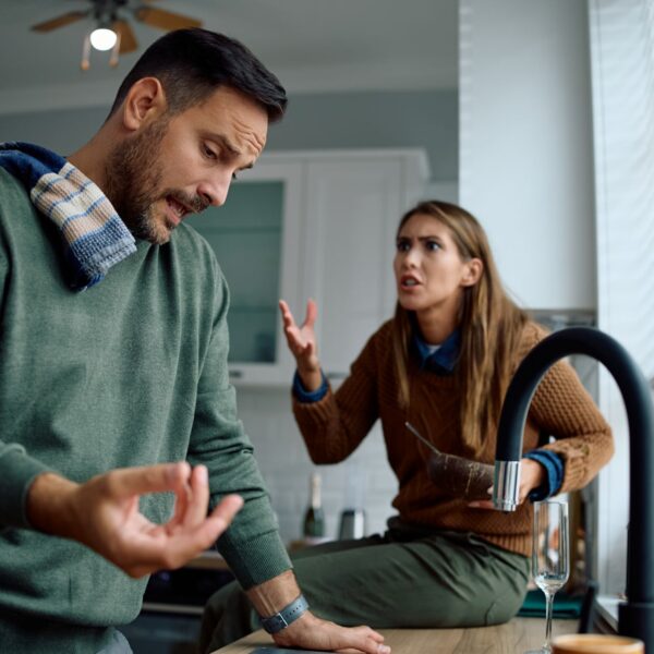Couple having a tense argument in a kitchen, illustrating communication problems and relationship conflict.