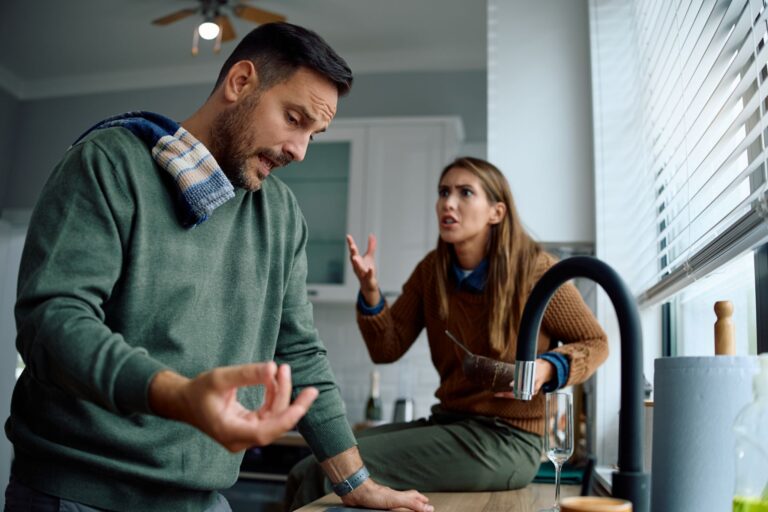 Couple having a tense argument in a kitchen, illustrating communication problems and relationship conflict.